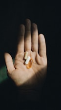 a hand holding two pills in the dark
