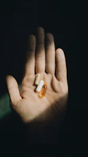 a hand holding two pills in the dark