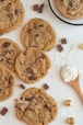 a table topped with chocolate chip cookies and a wooden spoon