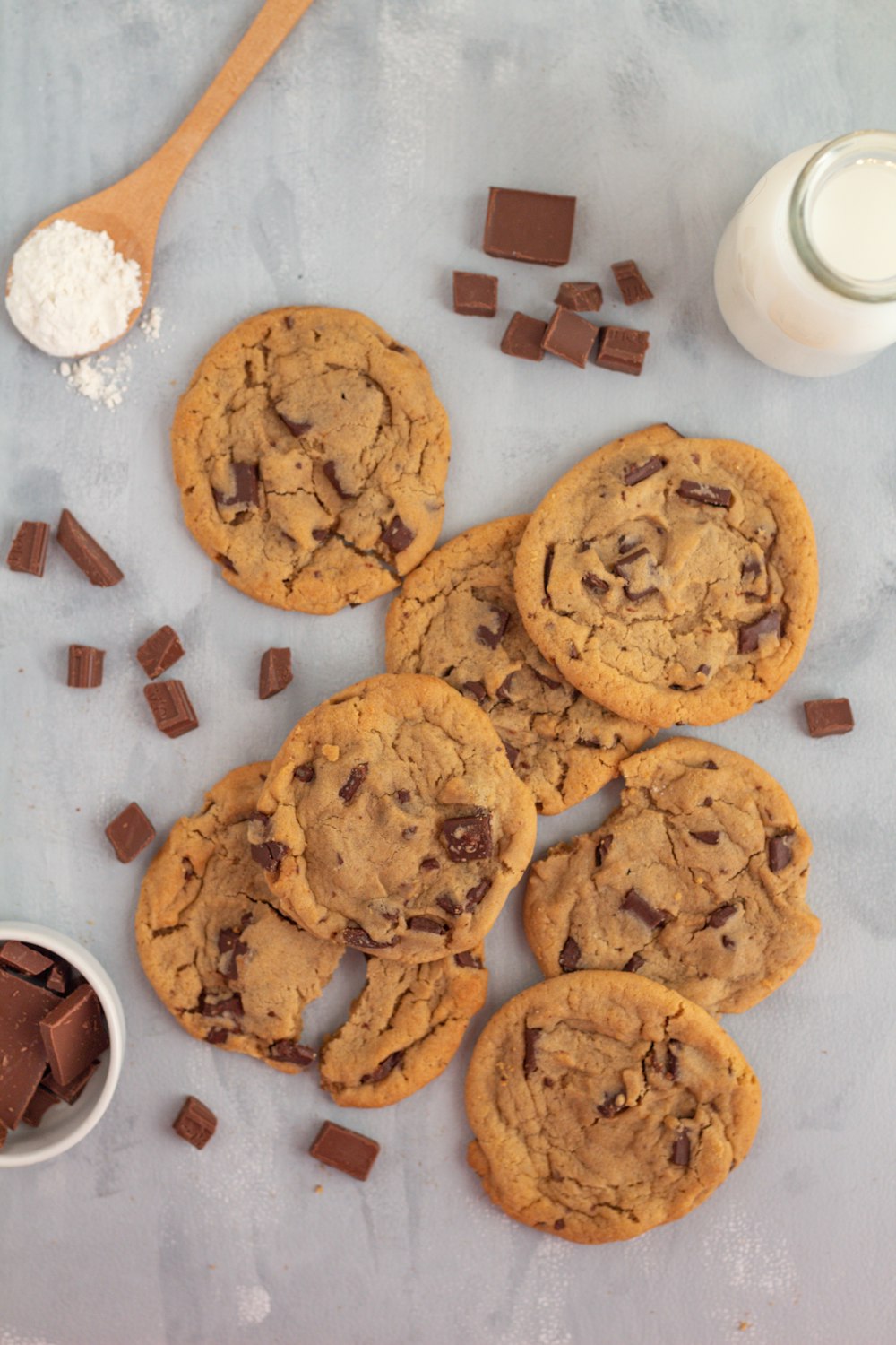 a table topped with chocolate chip cookies next to a glass of milk