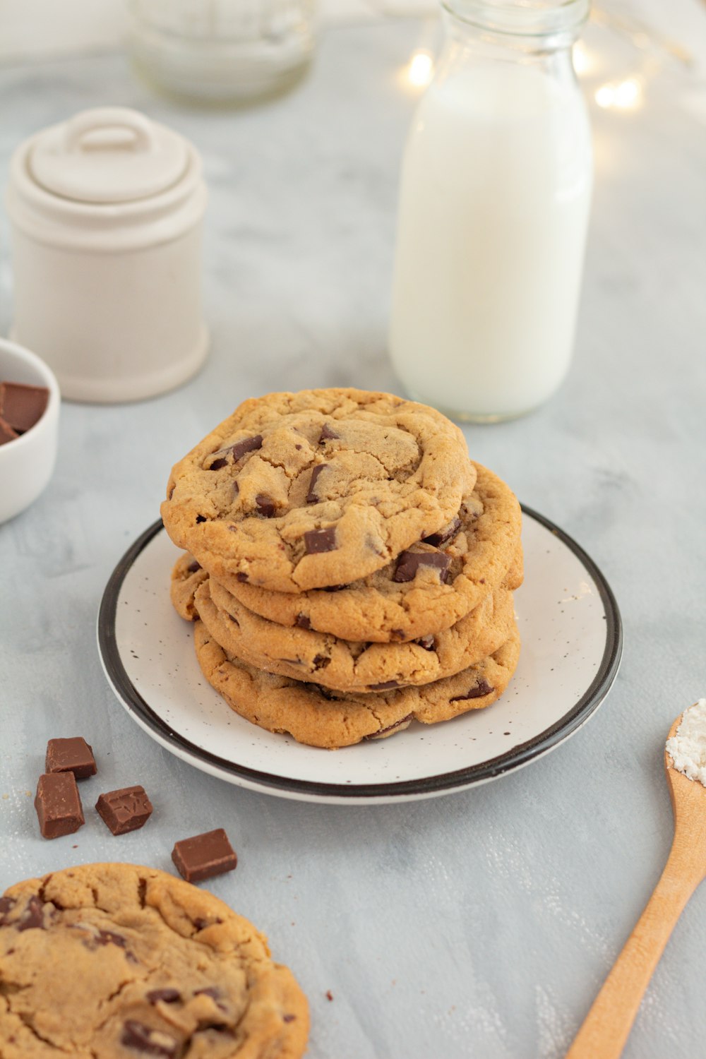 a stack of chocolate chip cookies on a plate next to a glass of milk