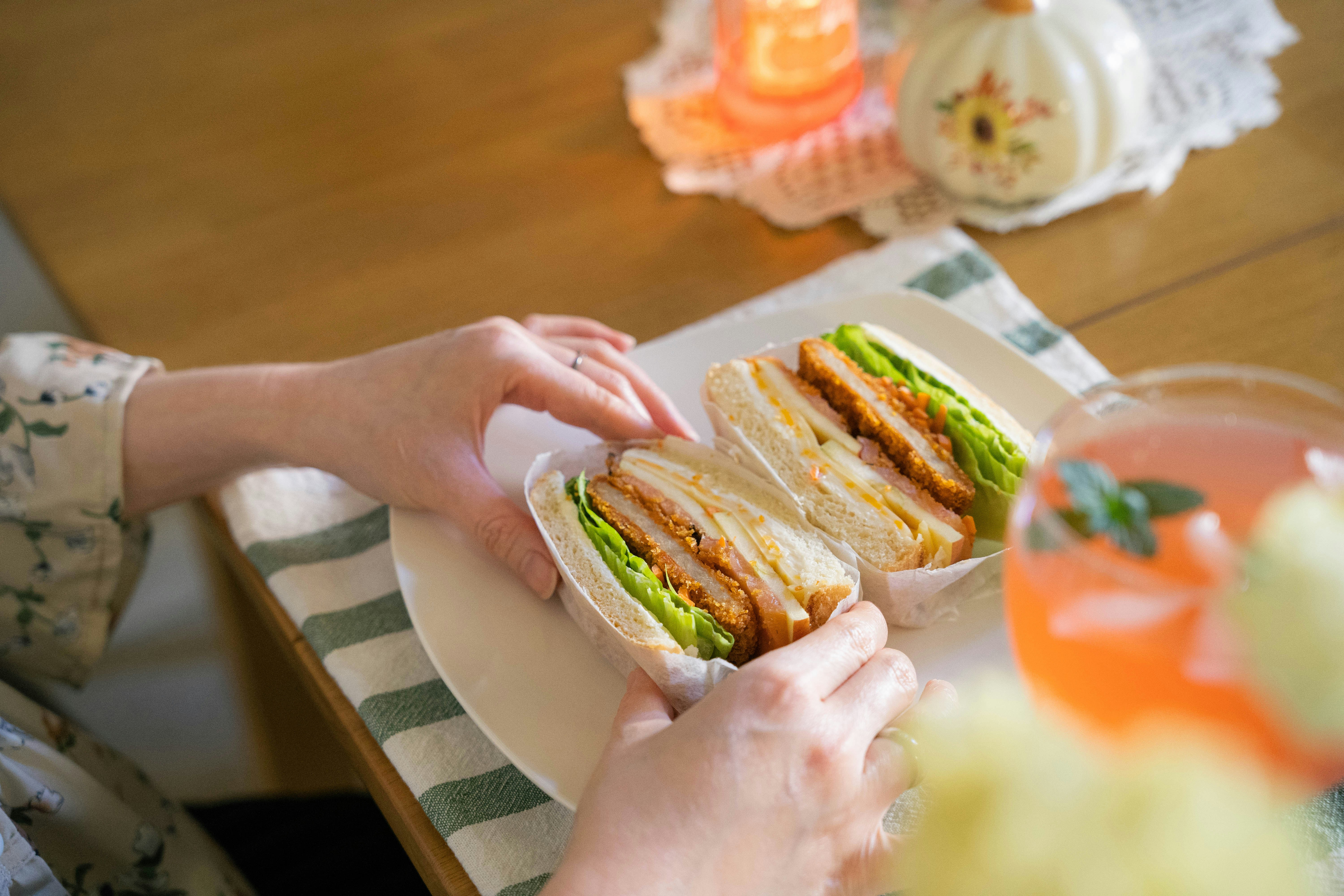 a person holding a sandwich on a plate
