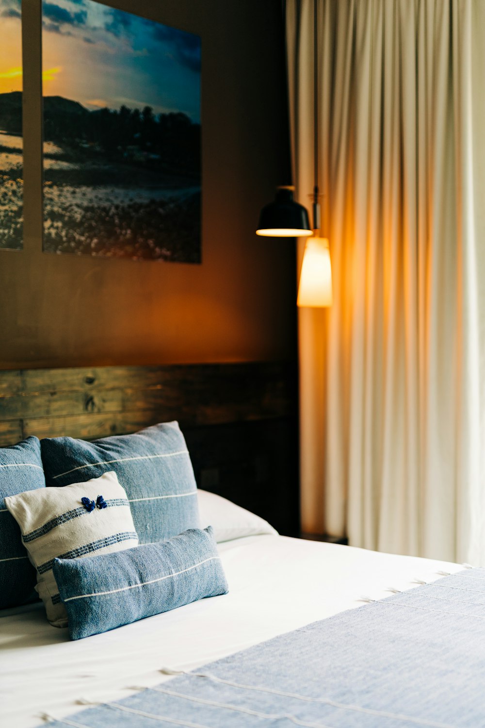 a bed with blue and white pillows and a painting on the wall