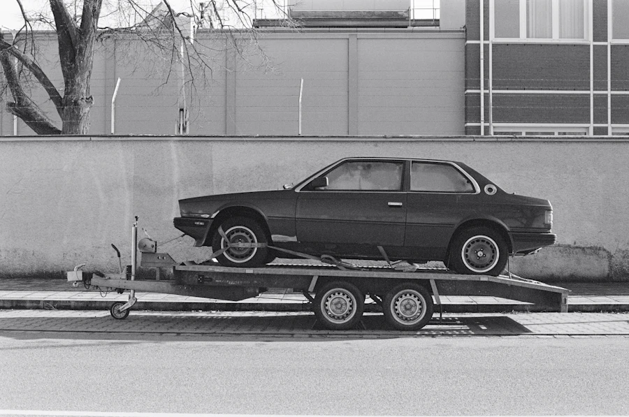 A sedan sitting level on an open flatbed deck beside a concrete wall