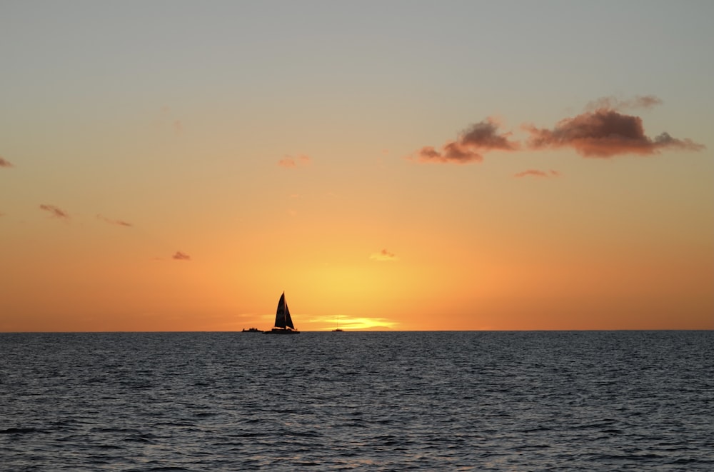 a sailboat in the ocean at sunset