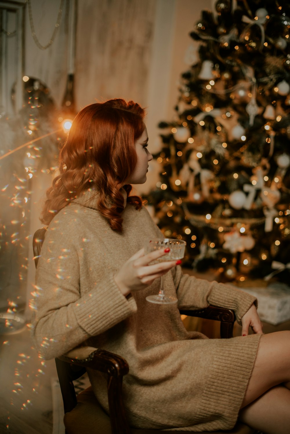a woman sitting in front of a christmas tree