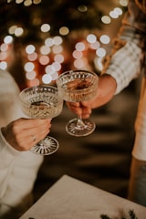 two people holding wine glasses in front of a christmas tree