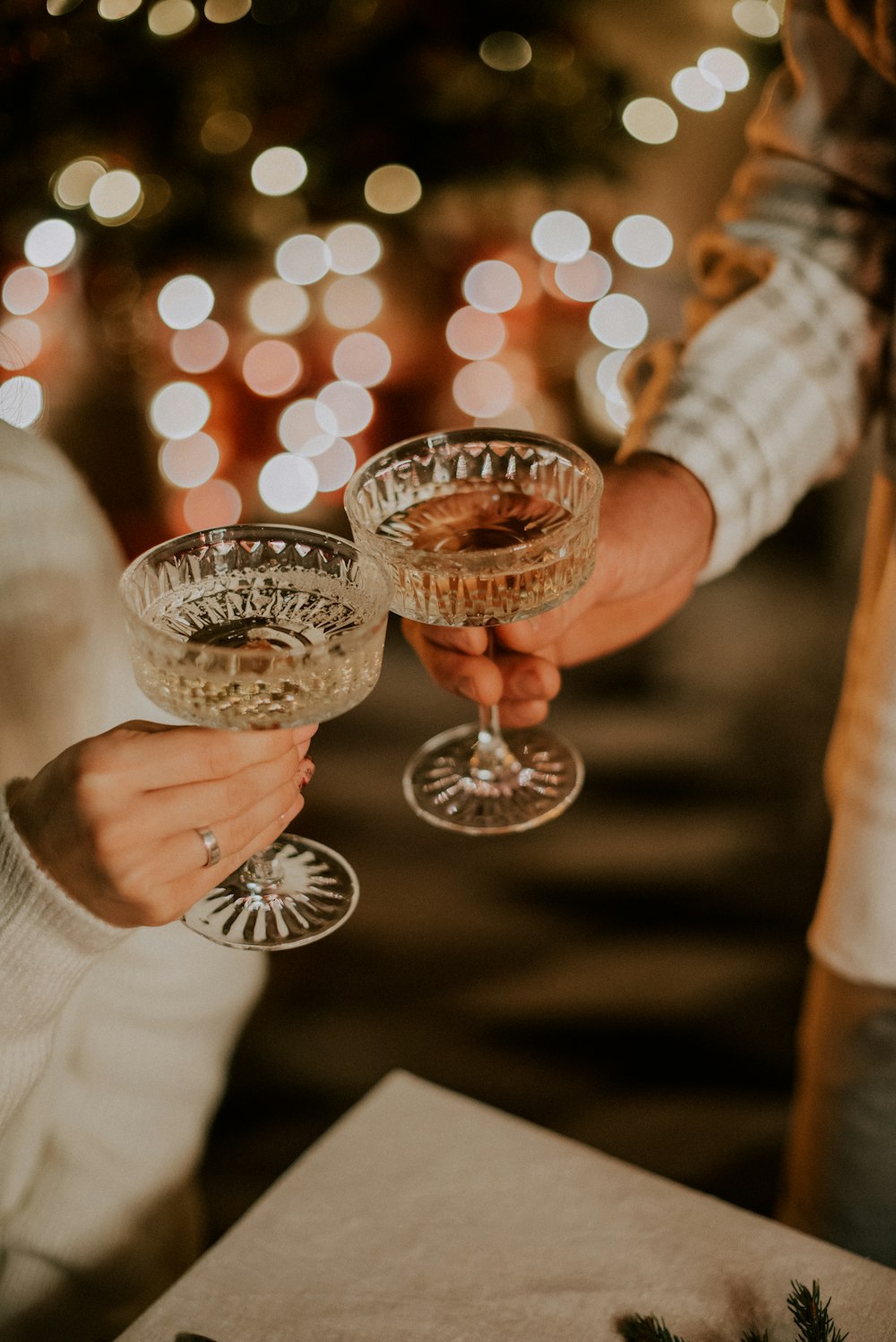 two people holding wine glasses in front of a christmas tree