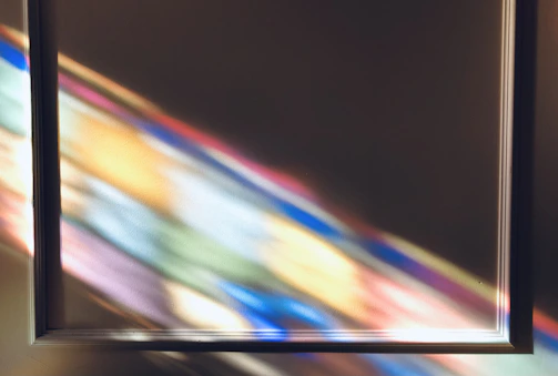 Bright rays of light streaming through a prism, casting multicolored reflections.