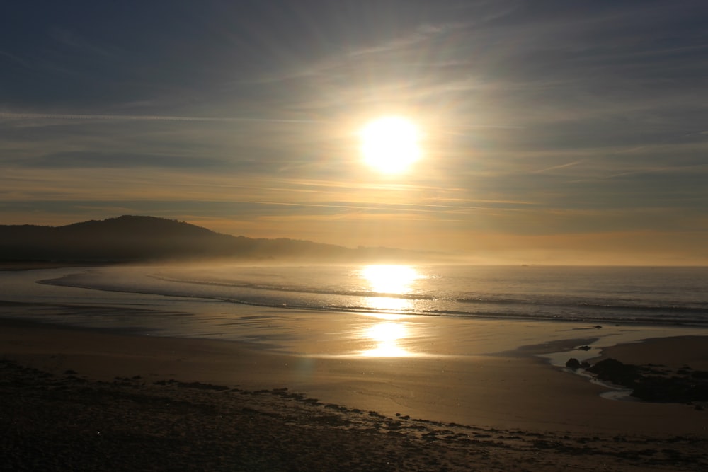 the sun is setting over the ocean on the beach