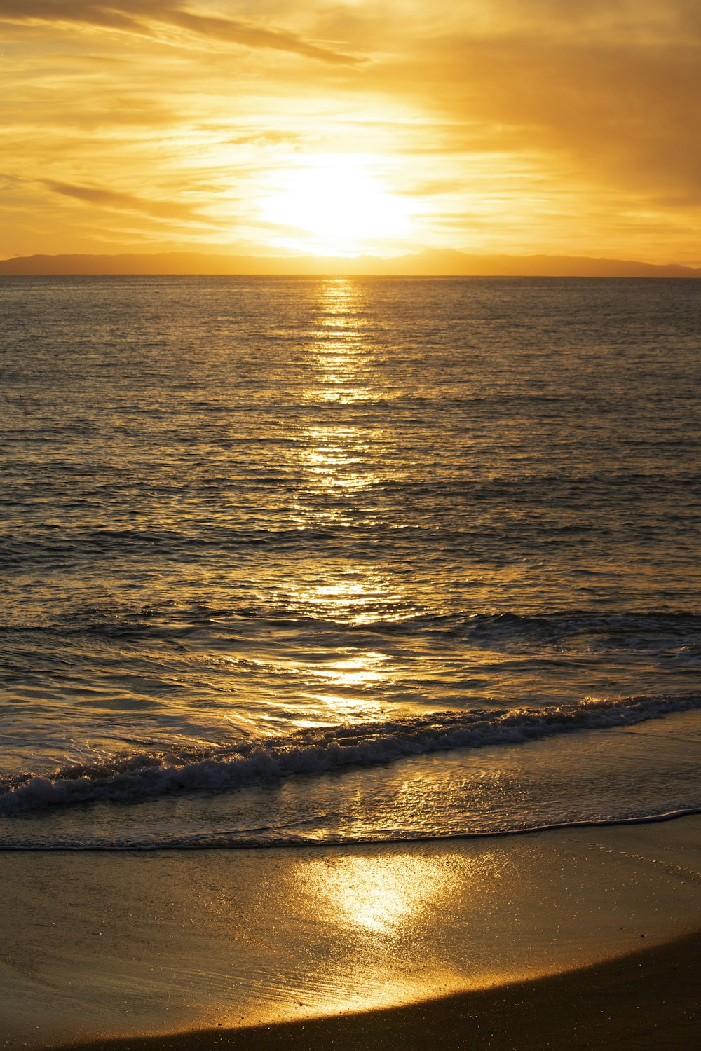 the sun is setting over the ocean on the beach