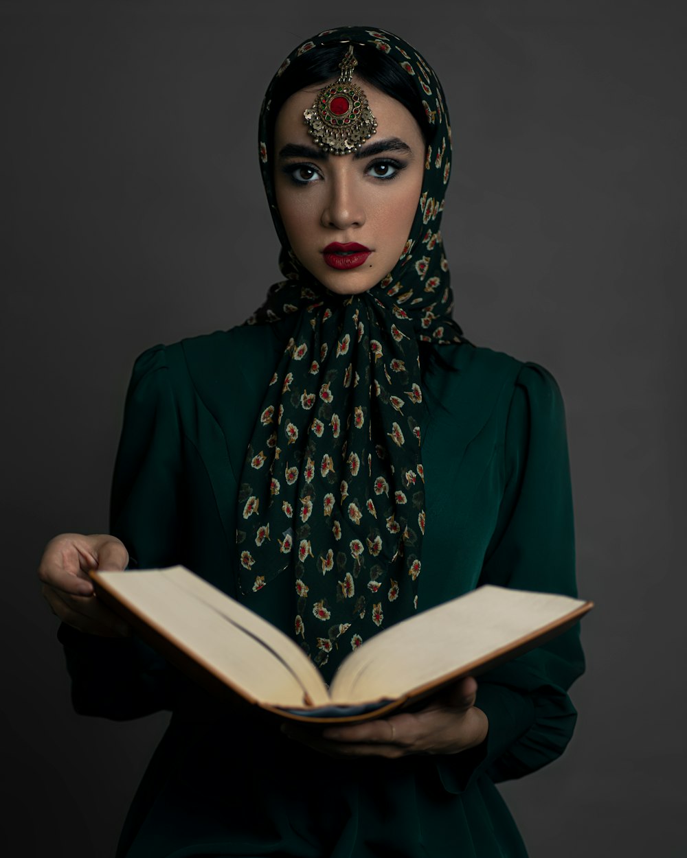a woman in a green dress is holding a book