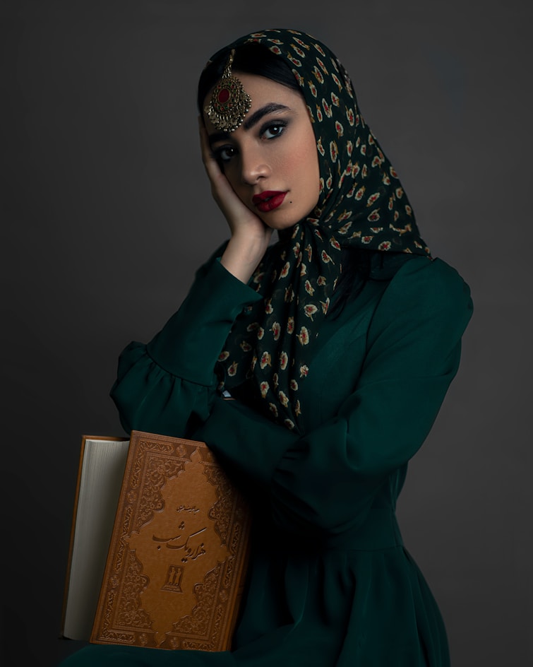 a woman in a green dress holding a book