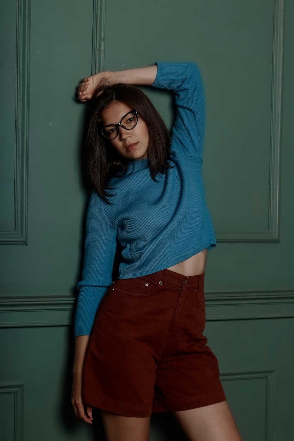 a woman in a blue sweater and brown shorts