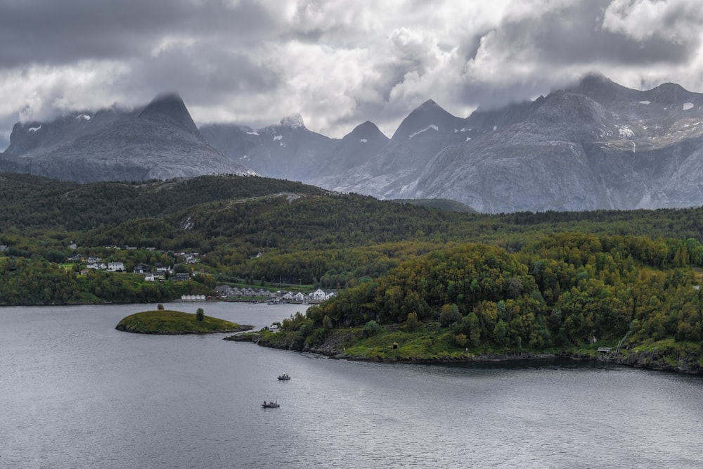 a body of water surrounded by mountains under a cloudy sky