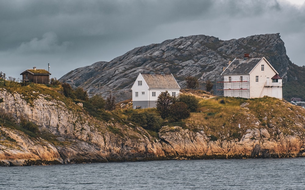 a couple of houses sitting on top of a hill next to a body of water