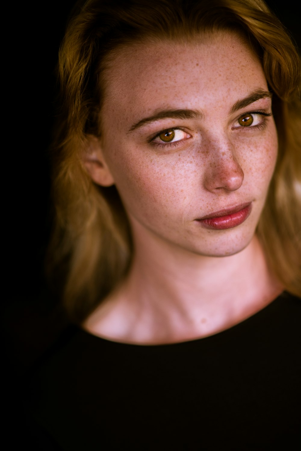 a woman with freckled hair and a black shirt