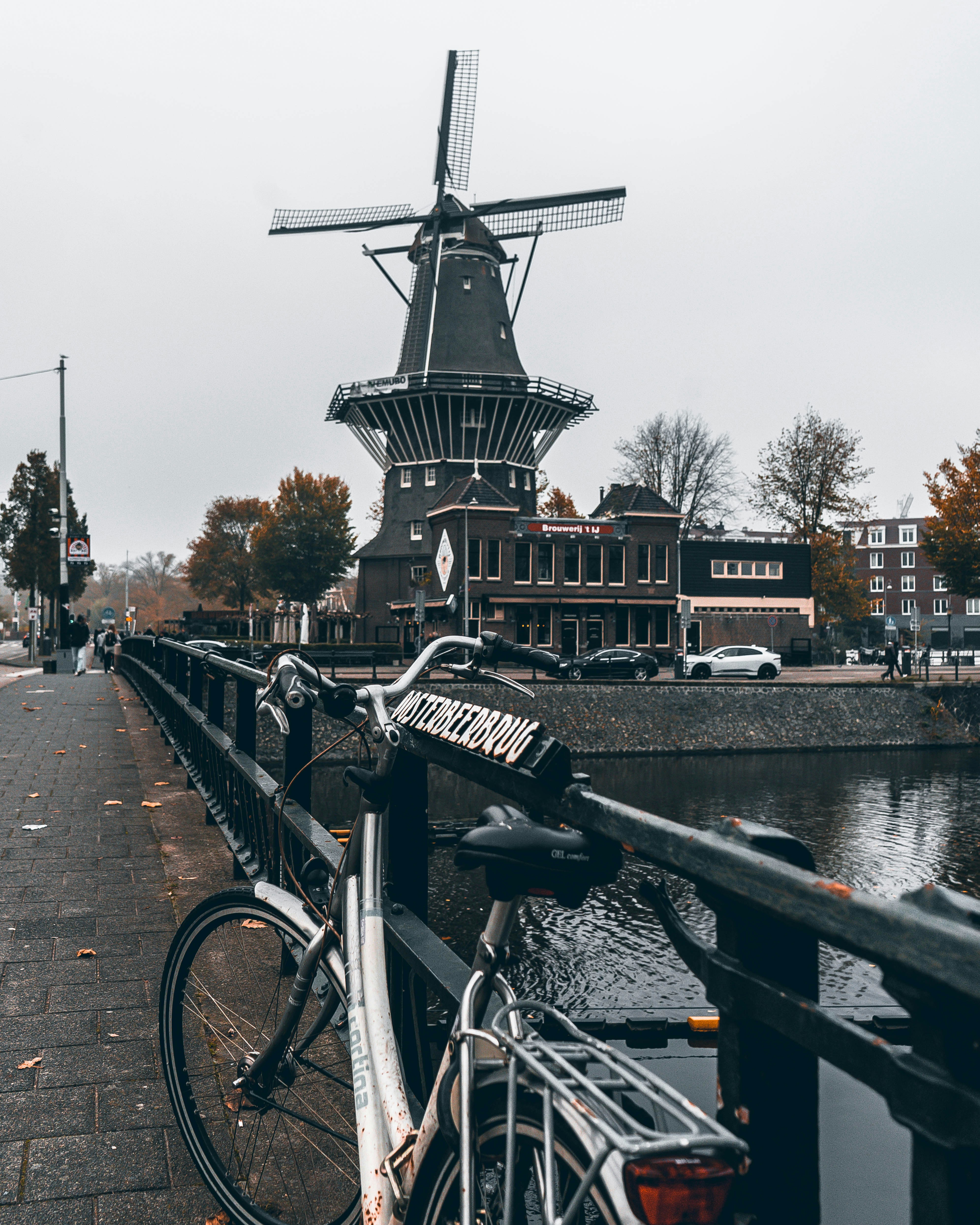 a bicycle parked next to a bridge with a windmill in the background