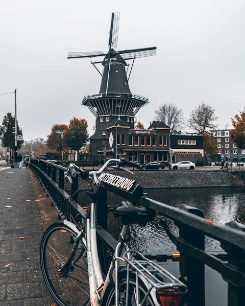 Vélo appuyé au garde-corps d'un pont, moulin en arrière-plan
