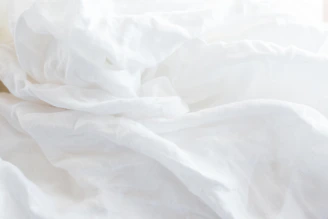 a close up of a bed with white sheets