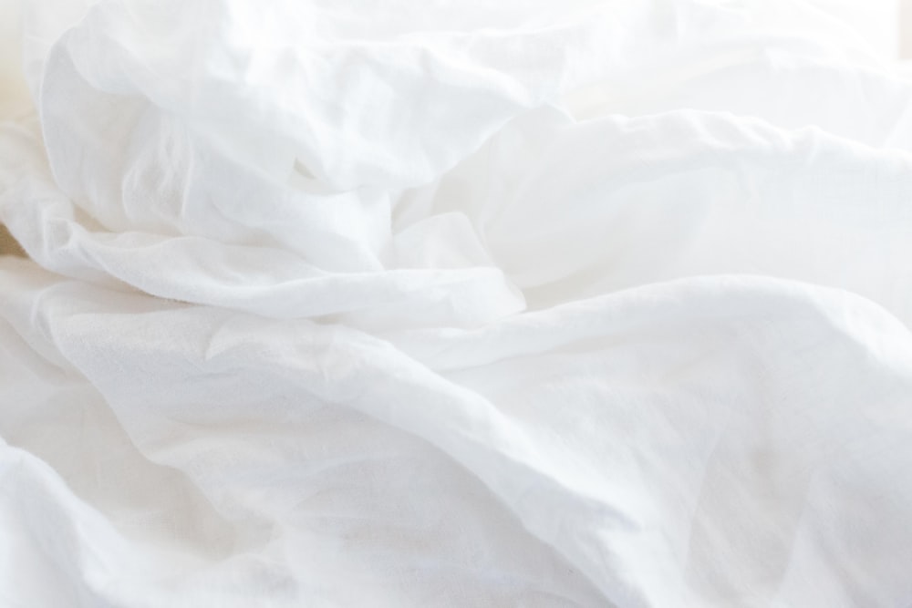 a close up of a bed with white sheets