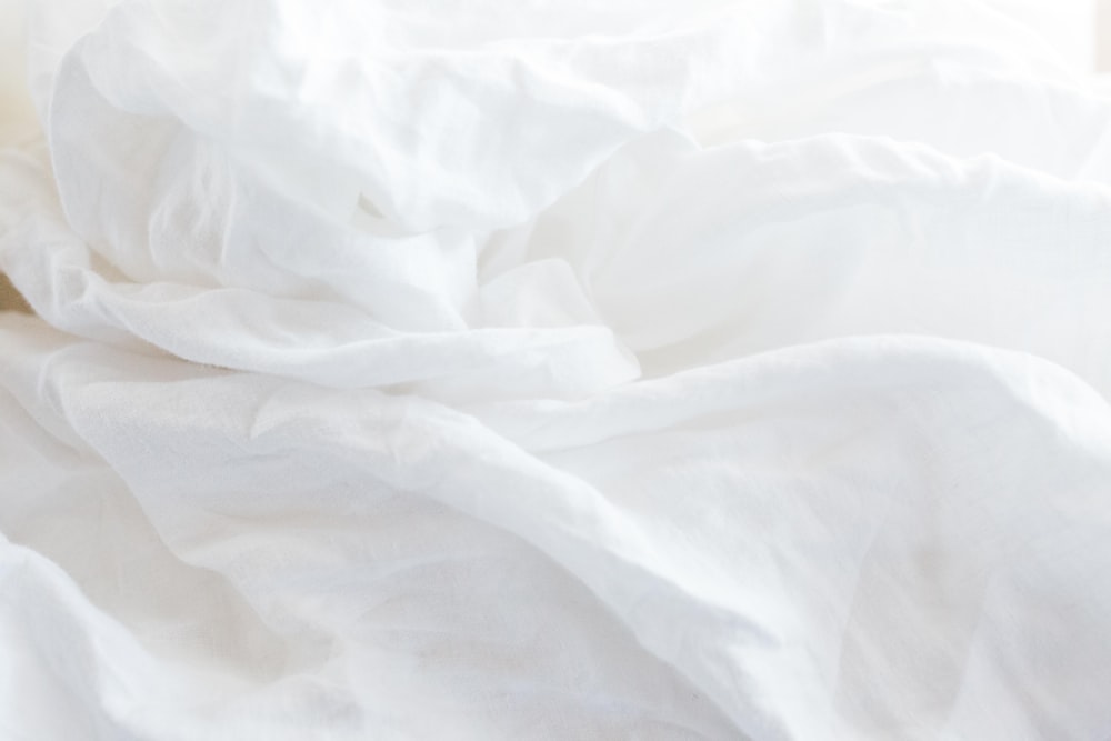 Un primer plano de una cama con sábanas blancas