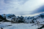 a snow covered mountain range with a lake in the foreground