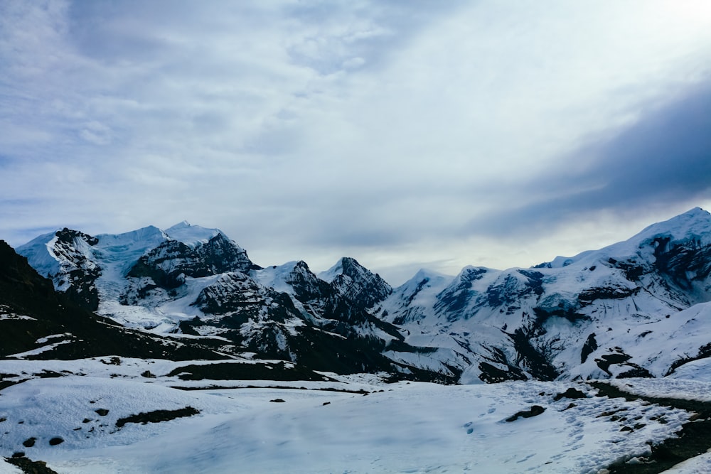 a snow covered mountain range with a lake in the foreground