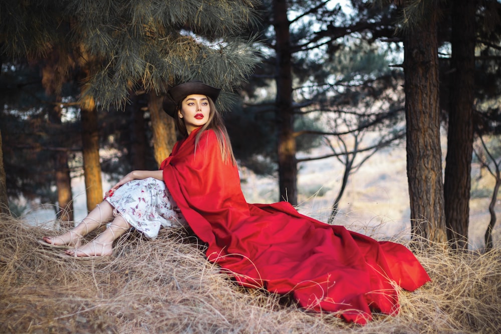 a woman in a red dress sitting in a field