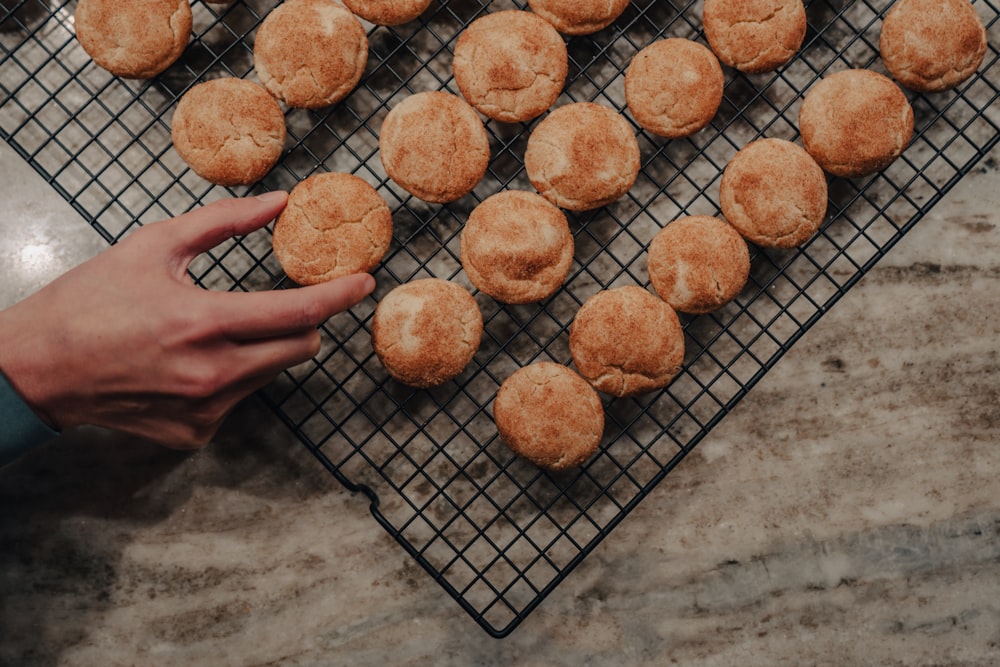 a person reaching for a cookie on a cooling rack