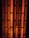 Vertical, elongated openings in a black metal grid with an orange, glowing background, creating an industrial appearance.