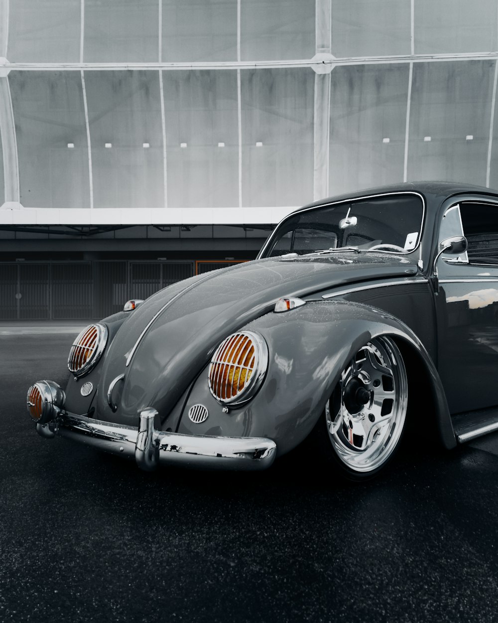 a gray vw bug is parked in a parking lot
