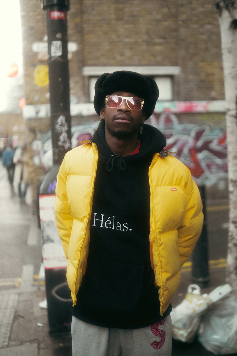 a man standing on a sidewalk wearing a yellow jacket