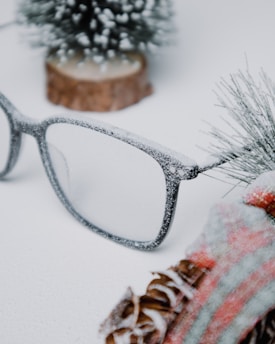 Cozy woolen scarves arranged on rustic wooden table with snowflakes gently falling nearby