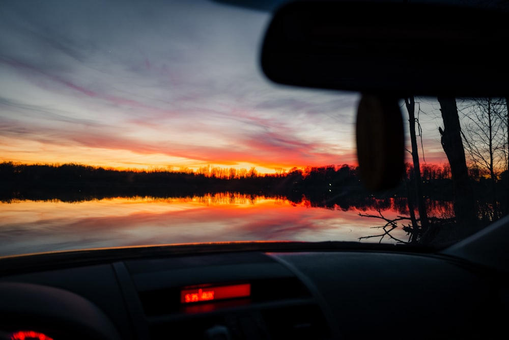 the sun is setting over a lake with trees in the background