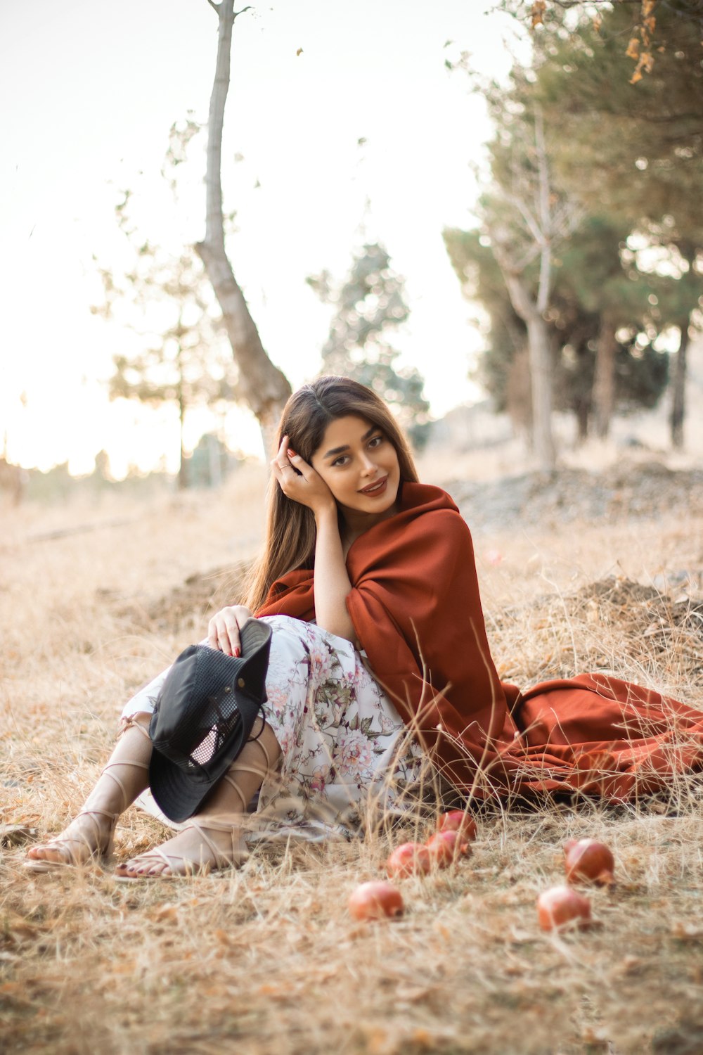 a woman sitting in a field with apples