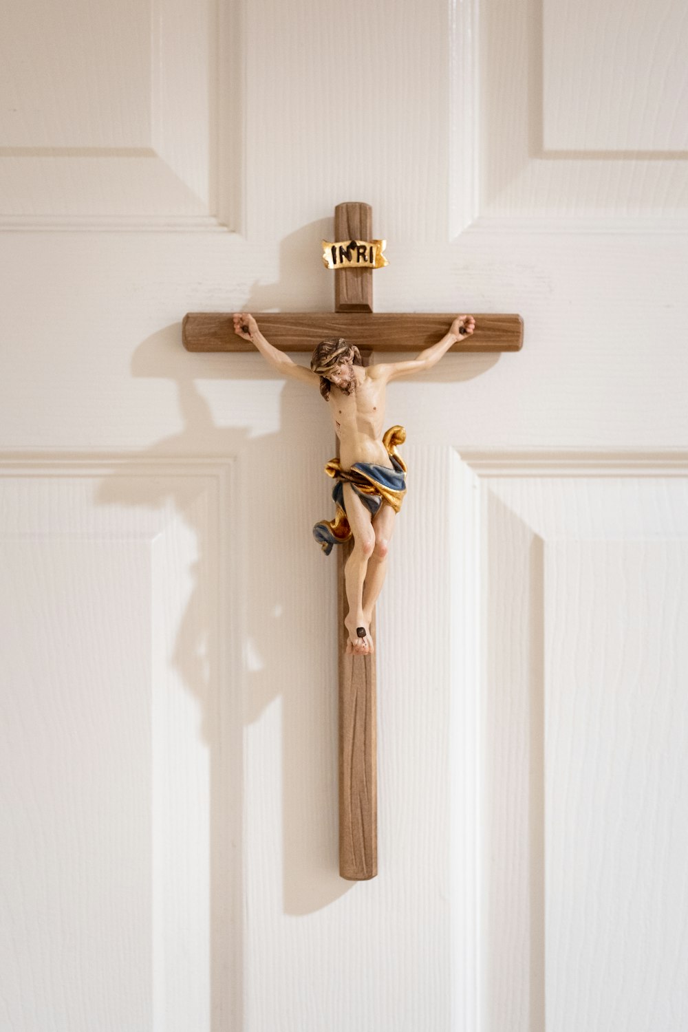 Un crucifijo de madera colgado de una puerta blanca