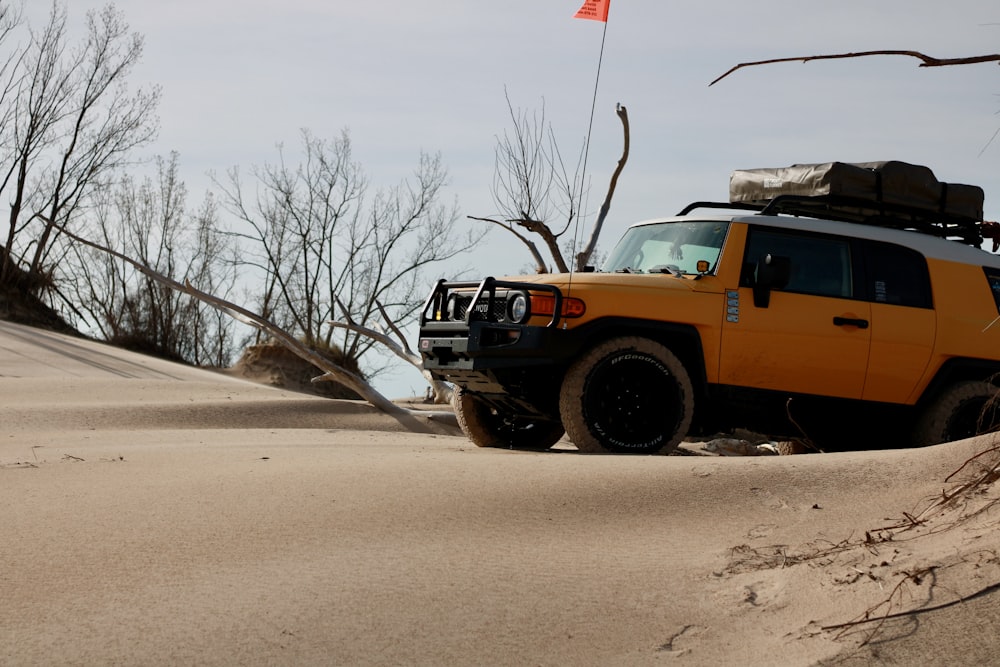 a yellow truck parked on top of a sandy hill