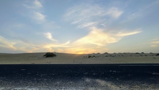 A serene sunrise over a winding desert road, symbolizing the journey with Road to Sinai.