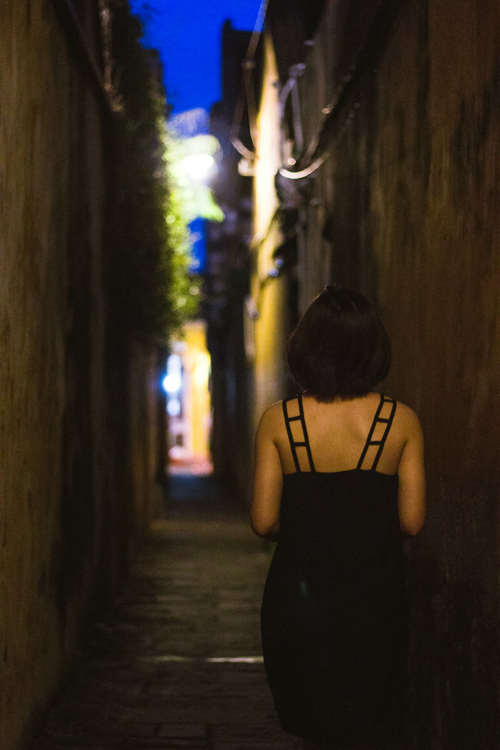 a woman walking down a narrow alley way