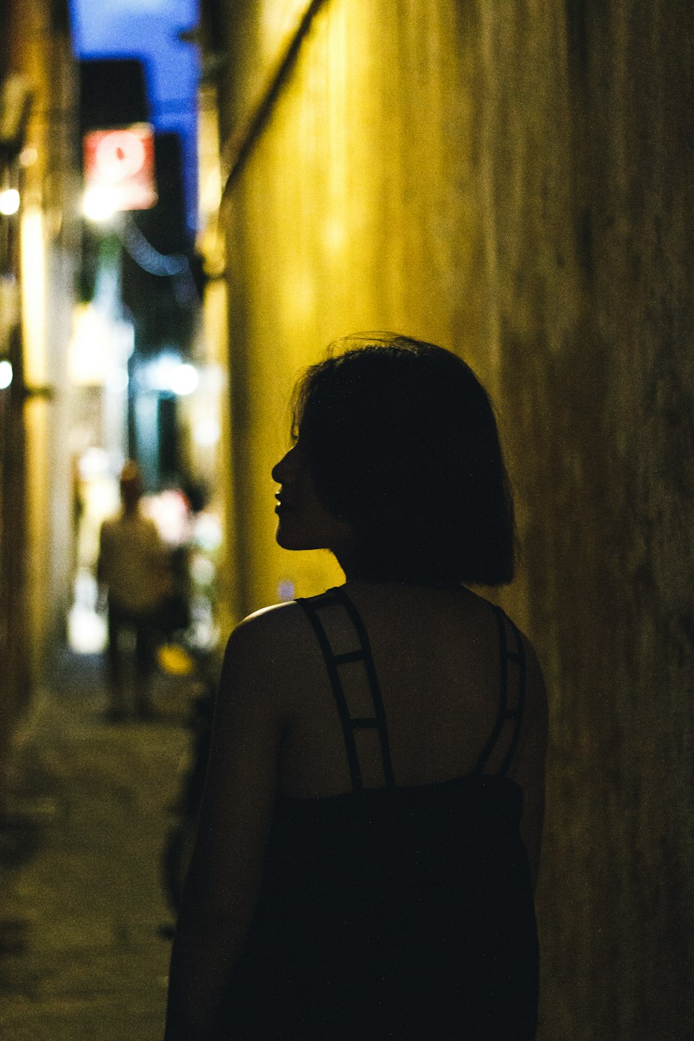 a woman standing in an alley at night