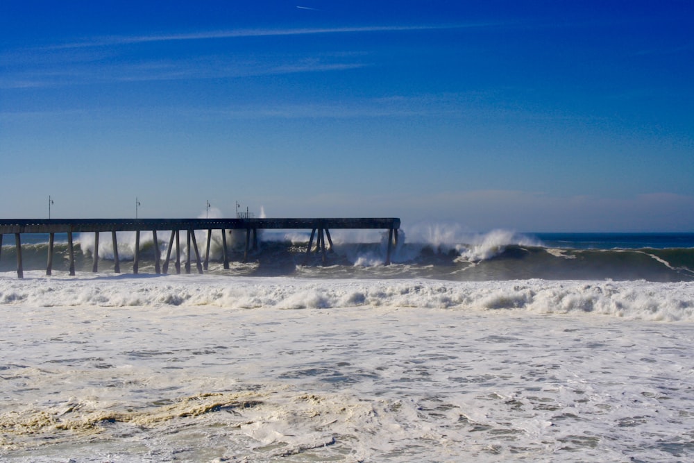 a long pier sitting on top of a beach next to the ocean