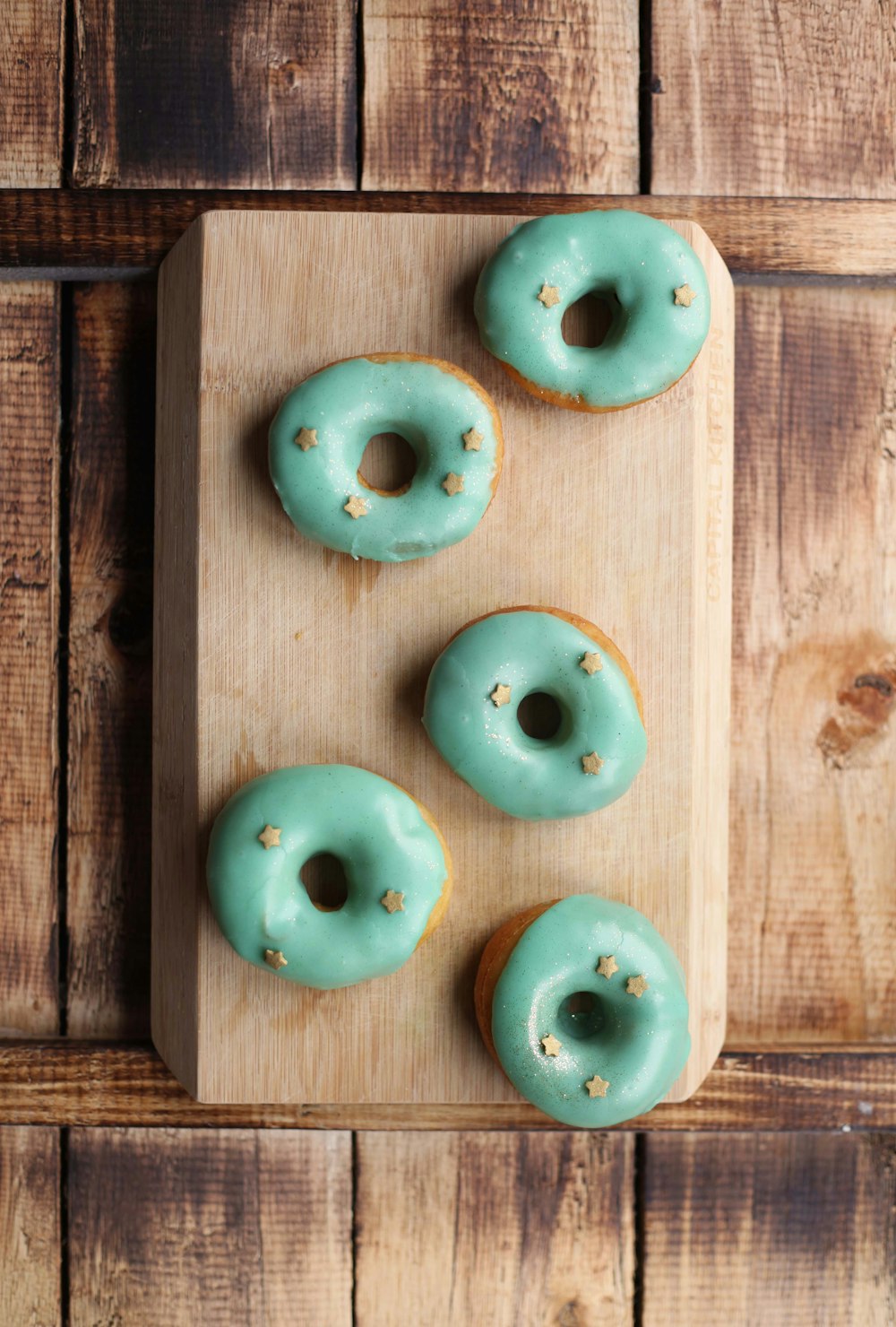 a wooden cutting board topped with donuts on top of a wooden table