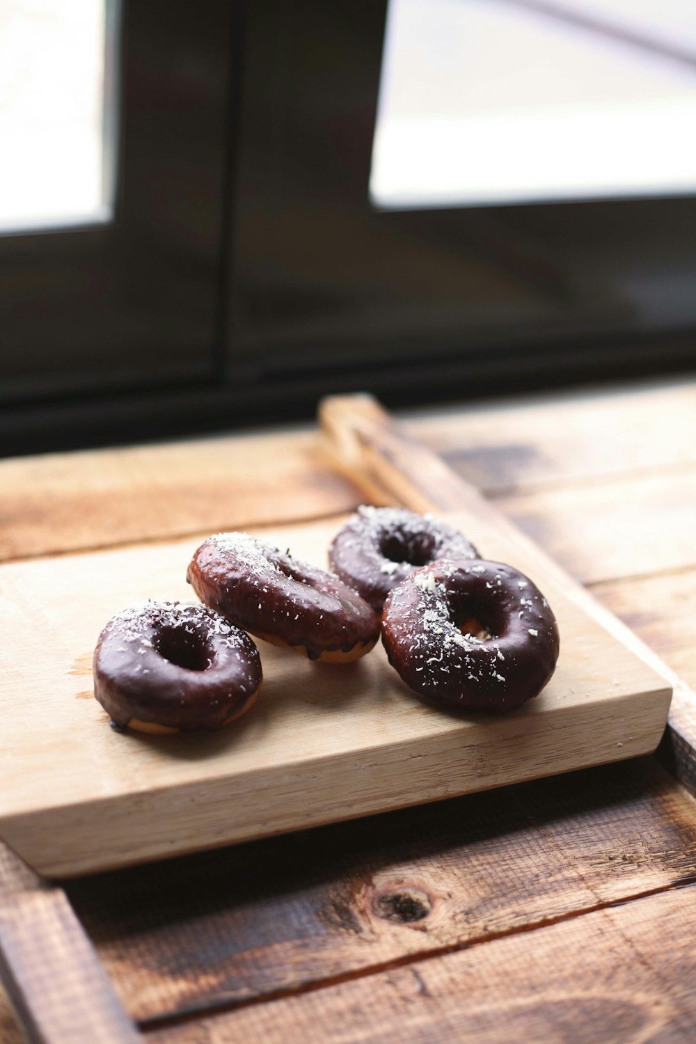 a wooden cutting board topped with three donuts