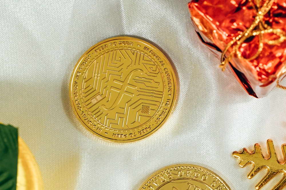 two gold coins sitting next to a wrapped present