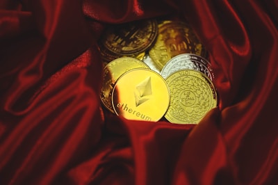 a pile of gold and silver coins sitting on top of a red cloth