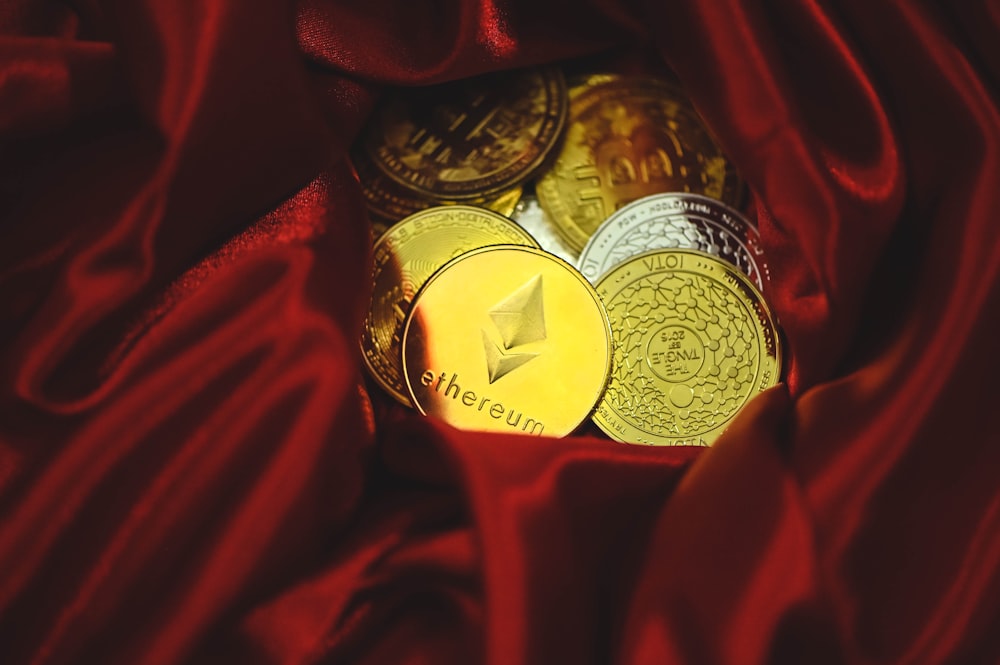 une pile de pièces d’or et d’argent posée sur un tissu rouge