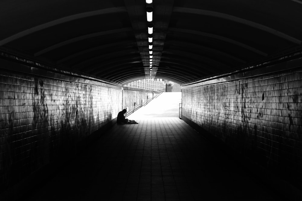a person sitting on the ground in a tunnel