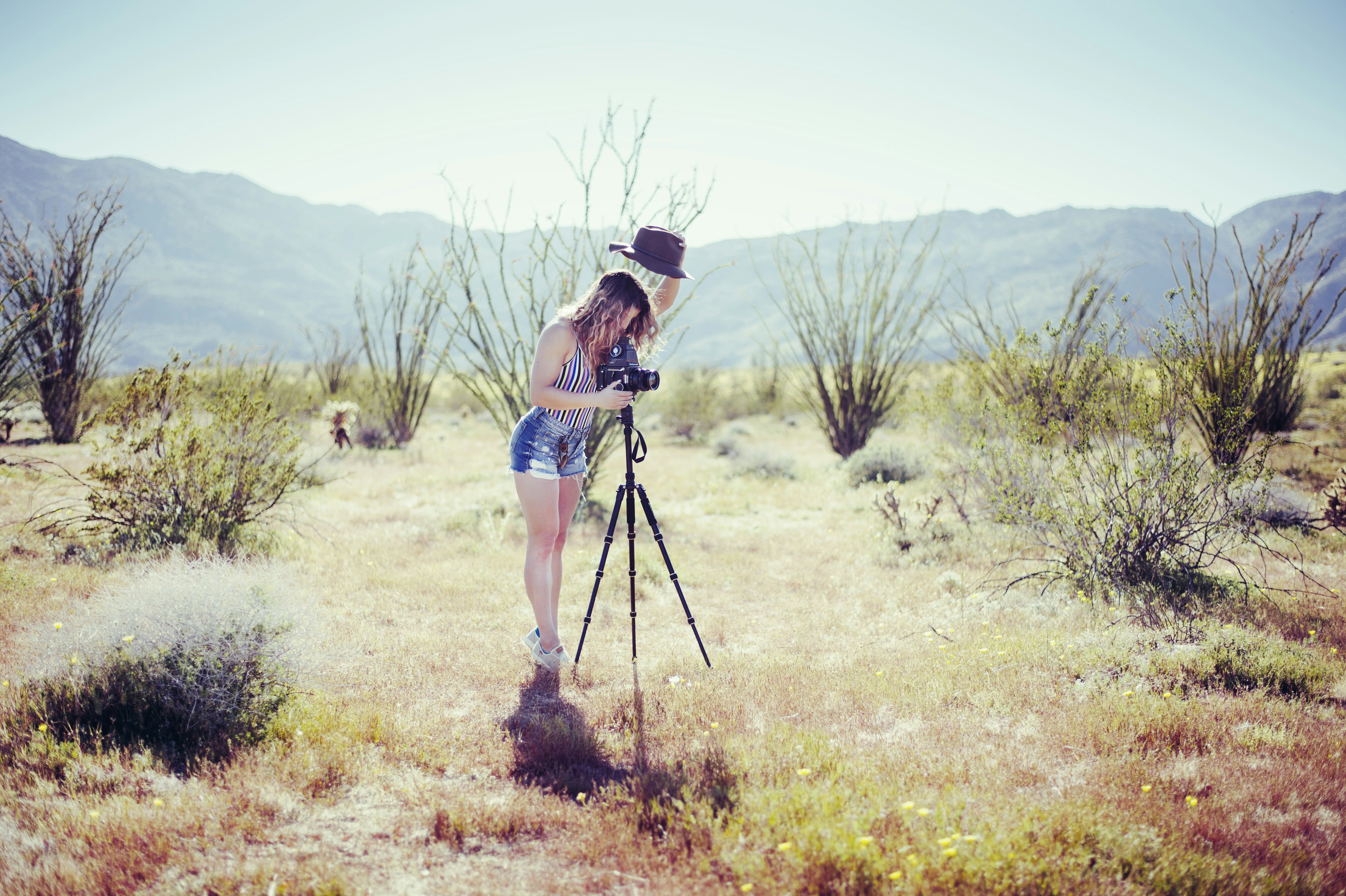 a woman standing in a field with a camera, 