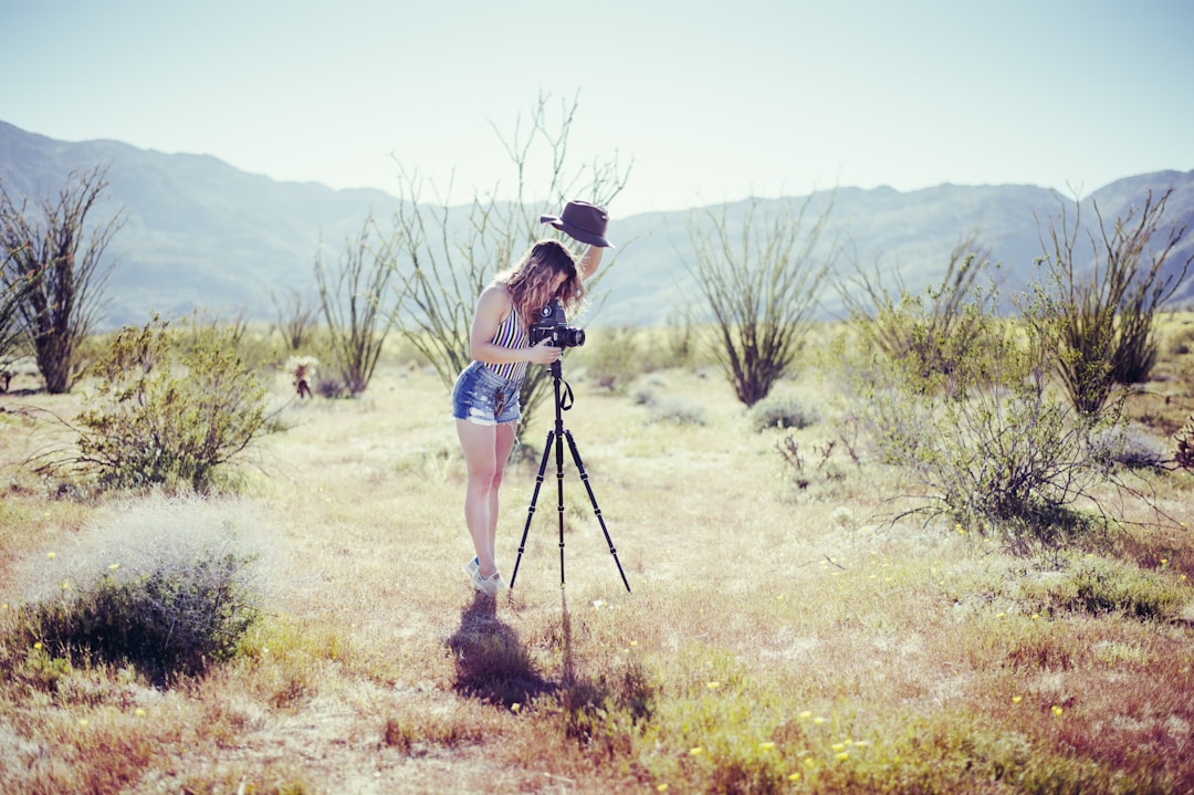a woman standing in a field with a camera,